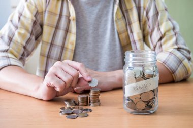 Seçici bir şekilde erkeklerin eline odaklan. Erkekler emeklilik fonu için para biriktirdikleri cam kavanoza para koyuyorlar. Günlük kıyafetlerle kapalı çekim yap..