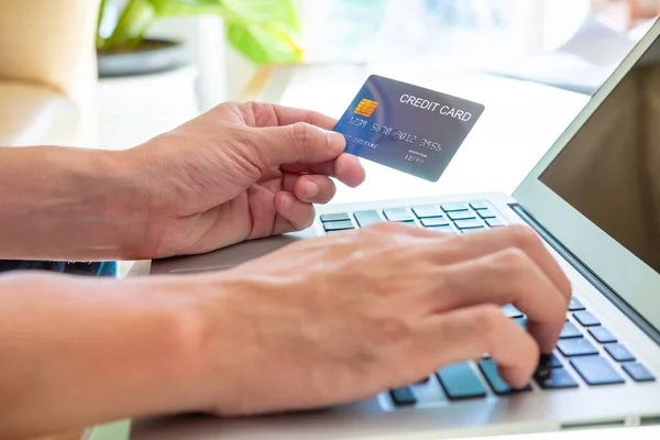 Selective focus at credit card mock up. Men hand hold credit card and type security information at computer keyboard to do online payment transaction. Secured online financial activity.
