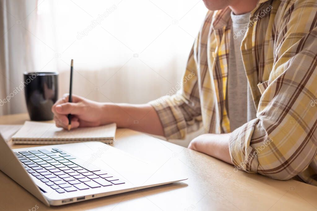 Selective focus at Asian men hand typing on computer laptop keyboard. Working or learning online with pc software apps technology concept, close up side view. New normal and social distance.