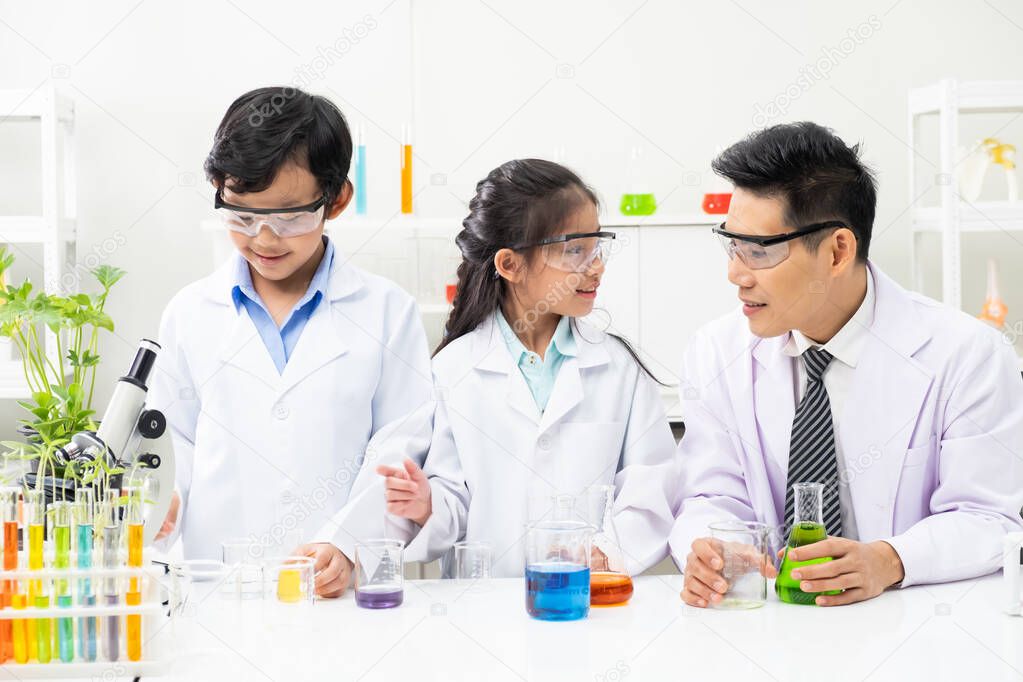 Young Asian boy and girl smile and having fun while learning science experiment in laboratory with teacher in classroom. Study with scientific equipment and tubes. Education concept.