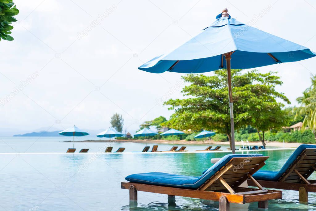 Beautiful tropical beach scenery with two beach bed with umbrella on the swimming pool. Luxury resort hotel with elegant natural viewpoint. Leisure and relaxation holiday with copy space for text.