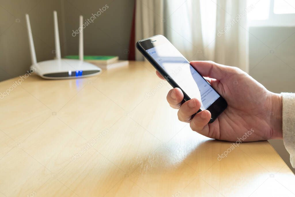 Men hand using smartphone device to connect to wifi network from internet router. Broadband high speed internet network technology for access to many application and services online.