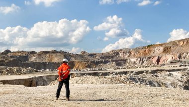 Taş, dağ ve mavi gökyüzü ile çevrili kaya ve beton madenlerinin manzarası. Kamyon ve sondaj makinesi kullanan endüstriyel mühendis ile. Endüstriyel kavram.