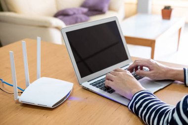 İnternet kullanırken bilgisayarın klavyesini yazarken erkeklerin eline odaklan. Evin içinde kablosuz bağlantı sağlayan yüksek hızlı internet yönlendiricisinin önünde.. 
