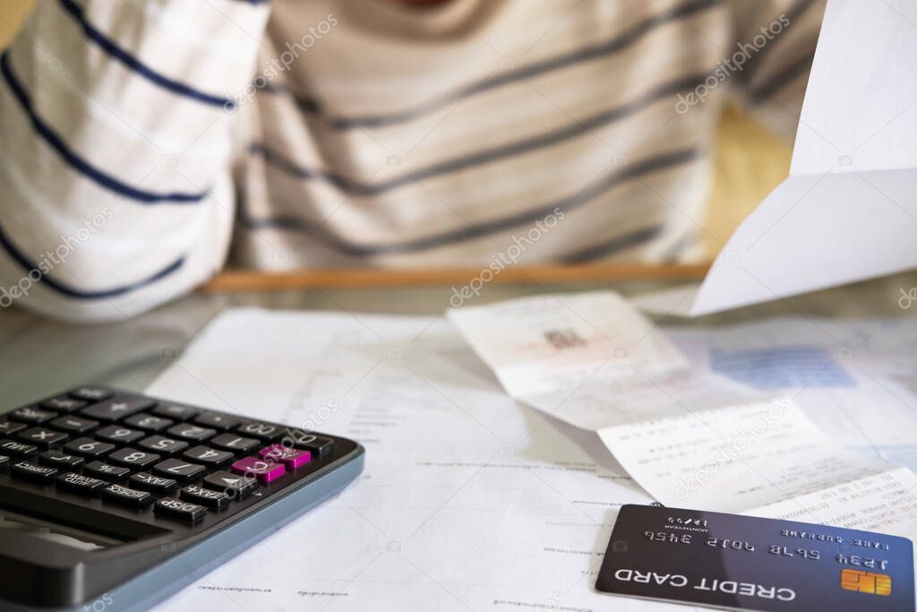 Selective focus at credit card mock up. Close up shot of people who check financial invoice and income statement and use calculator to calculate for personal or credit card expense. Money problem