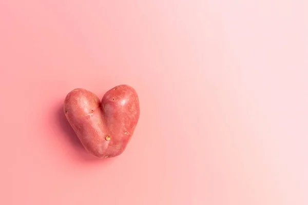 Картопля у формі серця на рожевому фоні — стокове фото