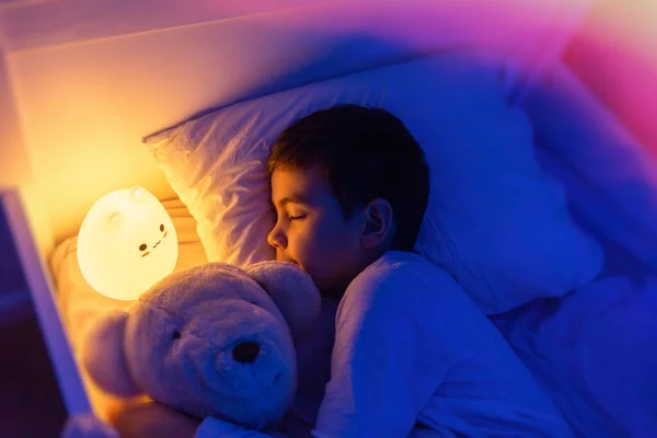 Çocuk gece lambasıyla uyuyor, yumuşak odaklı.