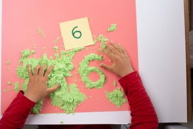 Çocuklar için kum tepsisi yazma, şekil verme ya da mektup yazma alıştırması, anaokulu yazma etkinliği, çocuk eli
