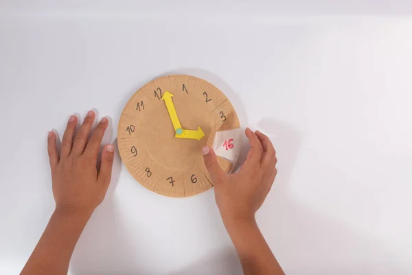 Actividad de enseñanza de hora preescolar, los niños aprenden a decir la hora en juguete reloj casero — Foto de Stock