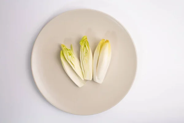 Escarola en la placa vista superior sobre fondo blanco, ensalada de raíces de achicoria, concepto de alimentos orgánicos saludables —  Fotos de Stock