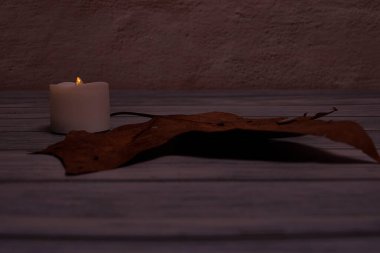 Ahşap arka planda mum ve düşen sonbahar yaprağı, ön manzara, boş alan