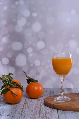 Bir bardak portakal suyu. Ahşap masa yeşil yapraklı portakallar parlak arkaplan