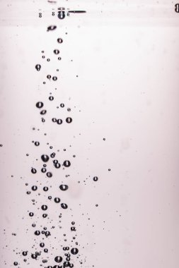 397.Su kabarcıklarının yakın plan görüntüsü, damlacıklar çarpıştıktan sonra berrak sıvıda yükseliyor, yansımalarla birlikte yuvarlak şekilleri detaylı olarak gösteriyor. Açık pembe arkaplan şeffaf kabarcıklara yumuşak karşıtlık ekler