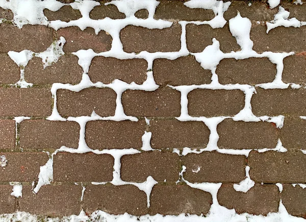 Met sneeuw bedekte stoep van rode tegels, sneeuw aan de voegen van de tegels, natuurlijke achtergrond — Stockfoto