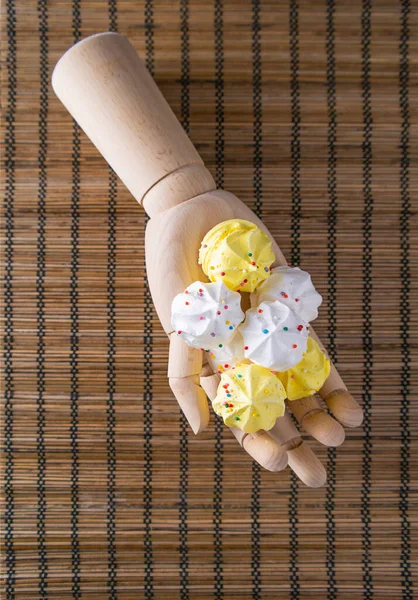 White and yellow Meringue cakes lie on a wooden hand — Stock Photo, Image