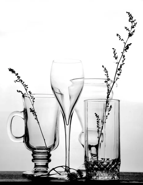 Transparent glass goblets and wine glasses and dry herbs on a light background, selective focus — Stock Photo, Image