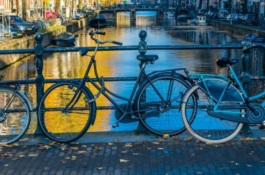 AMSTERDAM, NETHERLANDS - 17 Kasım 2018: Hollanda, Amsterdam 'da kanal üzerinde bisikletli bir köprü üzerinde tipik şehir manzarası