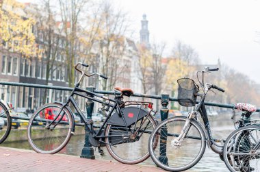 AMSTERDAM, NETHERLANDS - 16 Kasım 2018: Hollanda, Amsterdam 'da kanal üzerinde bisikletli bir köprü üzerinde tipik şehir manzarası