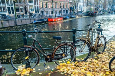 AMSTERDAM, NETHERLANDS - 17 Kasım 2018: Hollanda, Amsterdam 'da kanal üzerinde bisikletli bir köprü üzerinde tipik şehir manzarası
