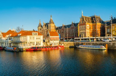 AMSTERDAM, NETHERLANDS - 17 Kasım 2018: Amsterdam 'daki merkezi tren istasyonu görüntüsü ve turist botları için bir rıhtım