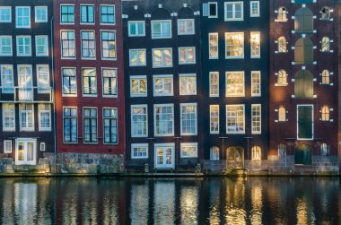 Kanal boyunca renkli evler ve Amsterdam, Hollanda 'daki sularda yansımaları.