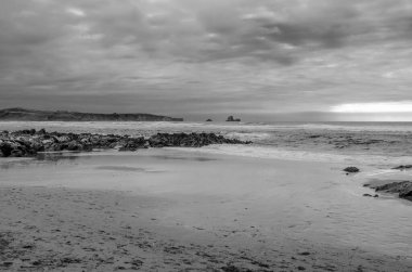 İspanya, Cantabria 'da gün batımında Valdearenas plajı manzarası. Siyah ve beyaz resim