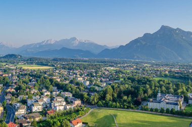 Avusturya 'nın Salzburg kentindeki yerleşim alanları, yeşil alanlar ve dağları gösteren Hohensalzburg Kalesi' nden manzara