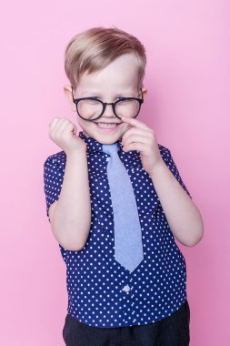 Portre küçük bir çocuk komik gözlük gülümseyen ve kravat. Okul. Okul öncesi. Moda. Stüdyo portre pembe bir arka plan üzerinde