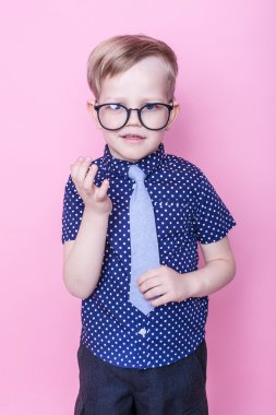 Portre küçük bir çocuk komik gözlük gülümseyen ve kravat. Okul. Okul öncesi. Moda. Stüdyo portre pembe bir arka plan üzerinde