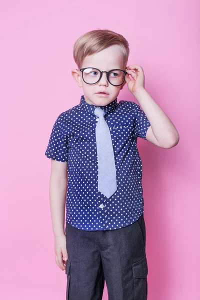 Menino adorável de gravata e óculos. Na escola. Pré-escolar. Moda. Retrato de estúdio sobre fundo rosa — Fotografia de Stock
