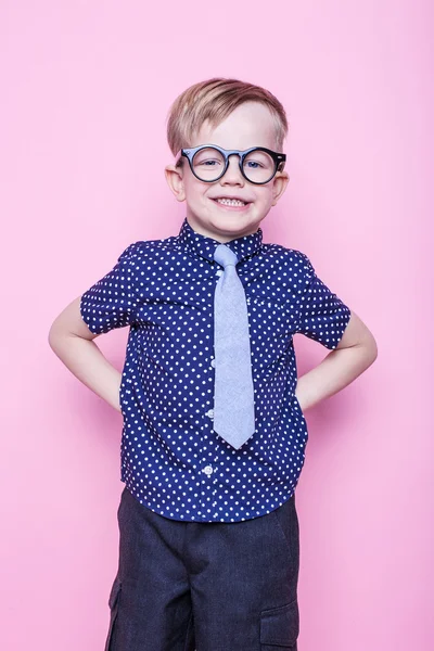 Um miúdo adorável de gravata e óculos. Na escola. Pré-escolar. Moda. Retrato de estúdio sobre fundo rosa — Fotografia de Stock