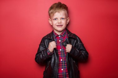 Moda çocuk deri ceketli. Stüdyo portre kırmızı bir arka plan üzerinde
