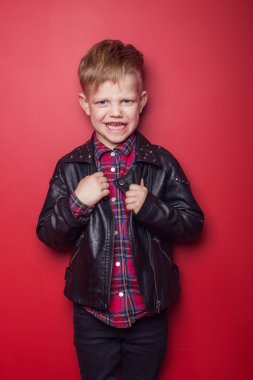 Moda çocuk deri ceketli. Stüdyo portre kırmızı bir arka plan üzerinde