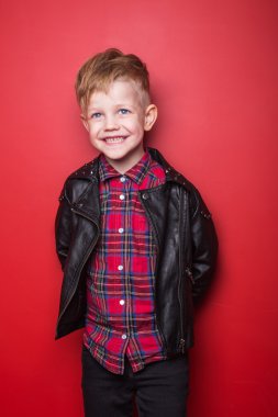 Küçük çocuk bir deri ceket moda. Stüdyo portre kırmızı bir arka plan üzerinde