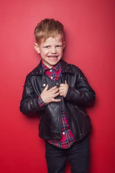 Divatos gyermek bőr kabát. Stúdió portré fölött piros háttér — Stock Fotó
