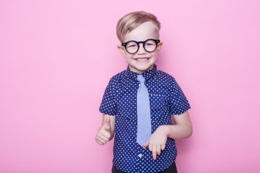 Portre küçük bir çocuk komik gözlük gülümseyen ve kravat. Tamam. Okul. Okul öncesi. Moda. Stüdyo portre pembe bir arka plan üzerinde