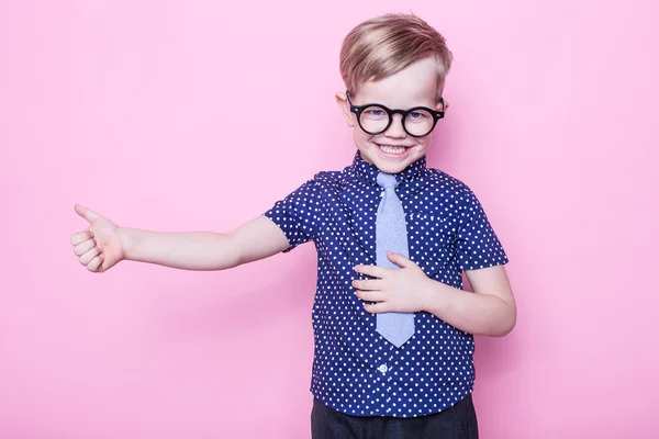 Retrato de um menino sorridente com óculos engraçados e gravata. Está bem, escola. Pré-escolar. Moda. Retrato de estúdio sobre fundo rosa — Fotografia de Stock