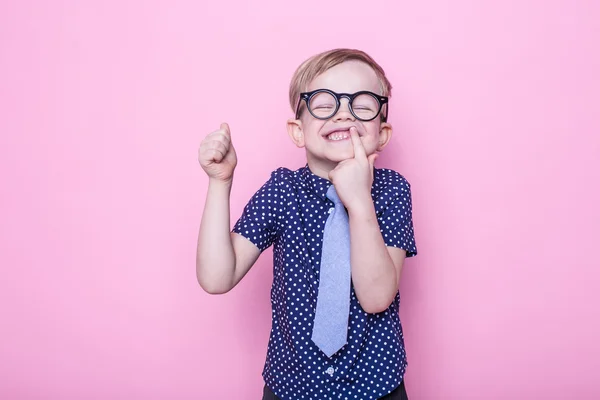 Retrato de um menino sorridente com óculos engraçados e gravata. Está bem, escola. Pré-escolar. Moda. Retrato de estúdio sobre fundo rosa — Fotografia de Stock