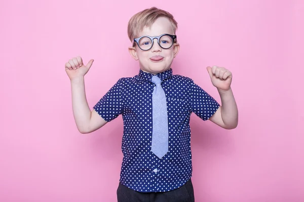 肖像的一点点微笑着滑稽眼镜的男孩，打领带。学校。学前班。时尚。工作室画像在粉红色的背景 — 图库照片