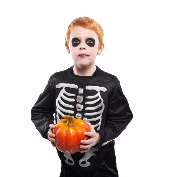 Retrato de un niño pelirrojo con disfraz de esqueleto de Halloween y calabaza en la mano — Foto de Stock