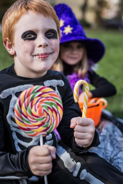 Ragazzo dai capelli rossi indossando costume scheletro di Halloween e tenendo caramelle colorate — Foto Stock