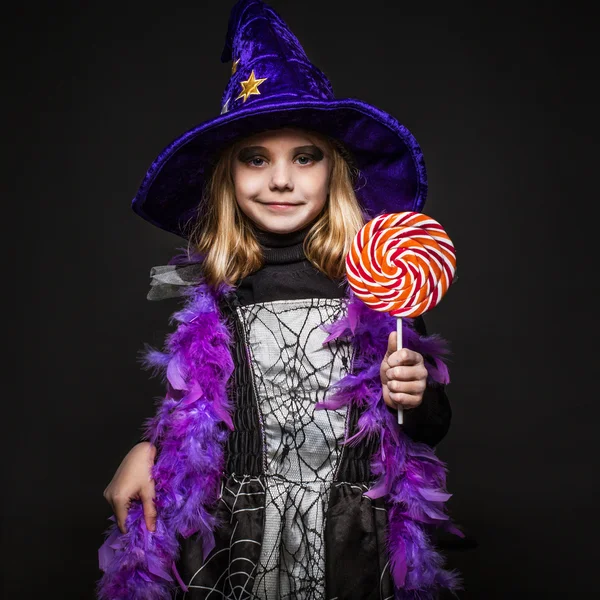 Kleine schöne Halloween-Hexe mit bunten Bonbons — Stockfoto