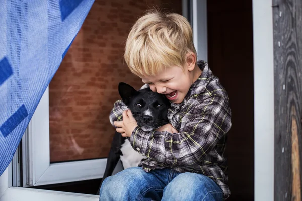 Güzel sarışın çocuk köpeğini kucaklamak. İnsan ve hayvan arasındaki dostluk — Stok fotoğraf