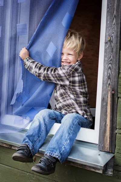 Beautiful blond kid sitting on window sill — Stock Photo, Image