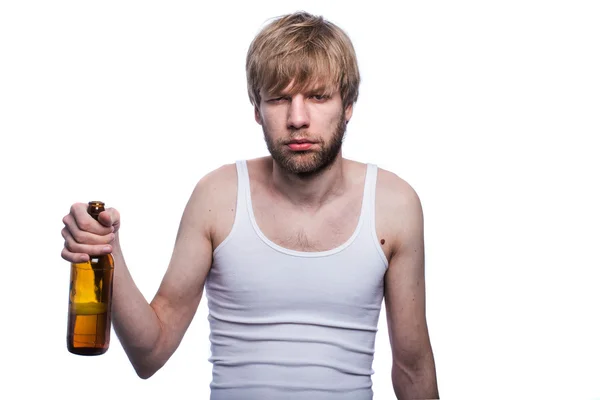 Молодой человек с похмельем держит бутылку пива. После вечеринки — стоковое фото