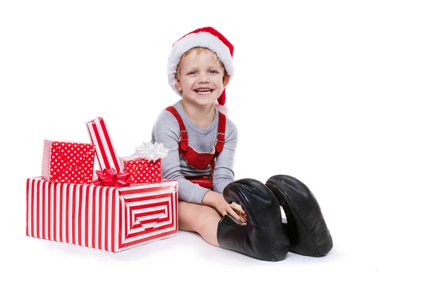 Concept: Christmas in childhood. Kid in red costume of dwarf with gifts — Stock Photo, Image