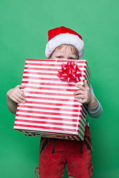 Little Kid in red costume of dwarf hiding behind red gift box — Stock Photo, Image