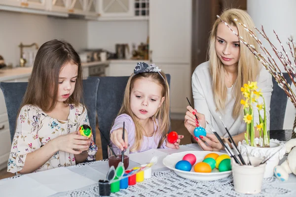 Jeune mère et ses deux filles peignant des œufs de Pâques — Photo