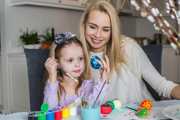 Young mother and her beautiful daughter painting Easter eggs — Stock Photo, Image