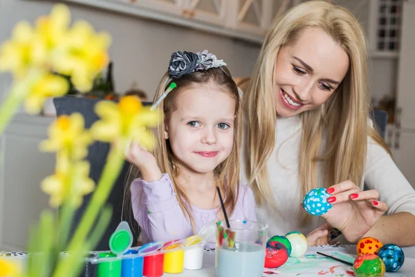 Young mother and her beautiful daughter painting Easter eggs — Stock Photo, Image